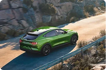 Green Ford Mustang Mach-E driving on a mountain road