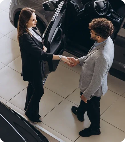 Dealership consultant shaking hands with a customer beside a vehicle