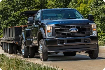 Ford Super Duty towing a flatbed trailer on a road