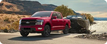 Red Ford F-150 towing a boat near the water