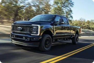 Black Ford Super Duty pickup driving on a road