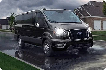 Black Ford Transit van on a wet residential street