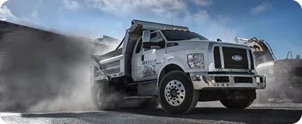 Ford dump truck hauling material through dust on a work site