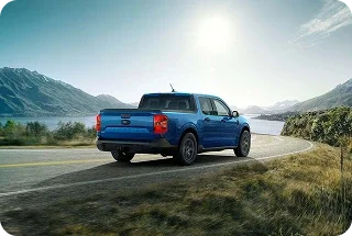 Blue Ford Maverick pickup on a lakeside mountain road