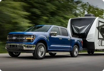 Blue Ford F-150 hybrid towing a travel trailer on the highway