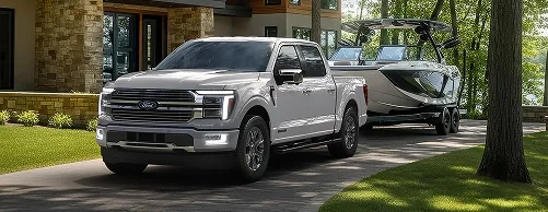 Ford pickup towing a boat on a tree-lined street
