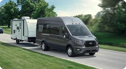 Ford Transit Passenger Van towing a travel trailer on a highway