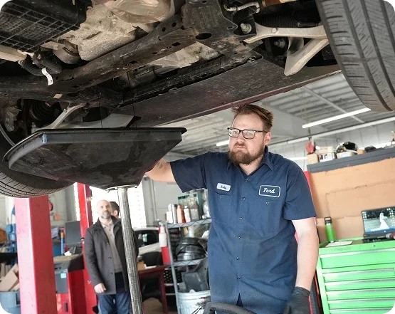 Ford technician working under a vehicle on a service lift