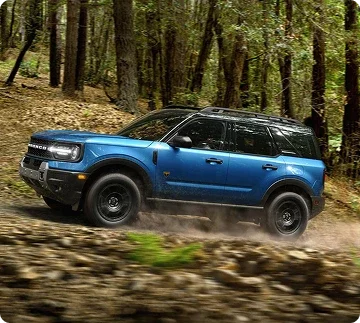 Blue Ford Bronco Sport driving on a wooded trail