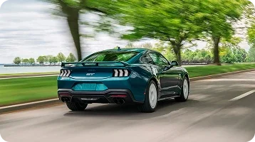Ford Mustang driving on a tree-lined road