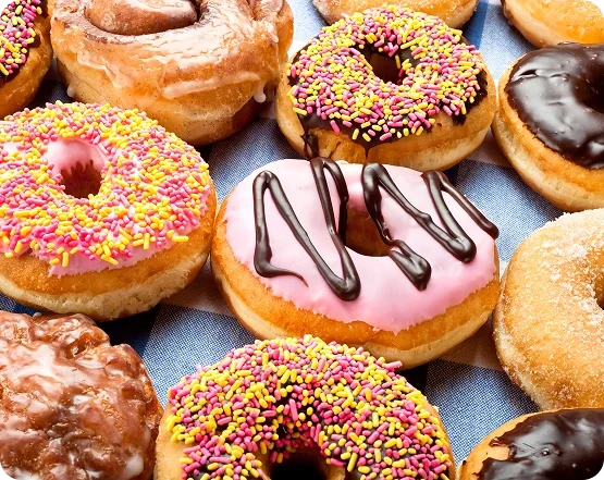 Assorted donuts with pink frosting, chocolate glaze and colorful sprinkles