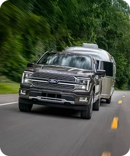 2026 Ford F-150 towing a travel trailer on a wooded road