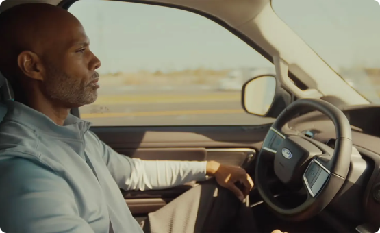 Driver steering a Ford on an open highway